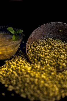 Close shot of mung bean or moong dal in a clay bowl along with some water and moong dal well mixed on a black glossy surface.Vertical shot with Rembrandt lighting technique.