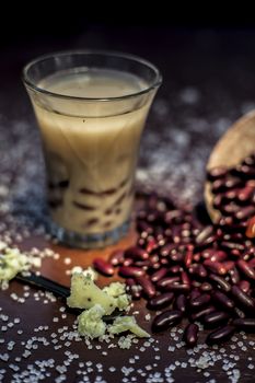 Red bean bubble tea in a glass along with some raw kidney beans, butter and sugar on the brown surface with Rembrandt light technique. Vertical shot.
