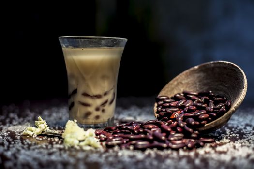 Red bean bubble tea in a glass along with some raw kidney beans, butter and sugar on the brown surface with Rembrandt light technique. Horizontal shot.