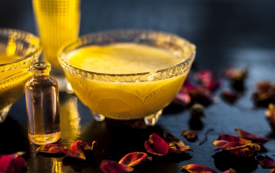 Natural hair remedy for healthy hair consisting of some coconut oil well mixed with olive oil, ghee and essential oil. Entire ingredients present on the surface with prepared oil in a glass bowl.