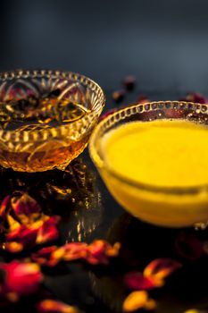 Ayurvedic moisturizer face mask on black glossy surface in a glass bowl with some ghee or clarified butter, honey and pack.