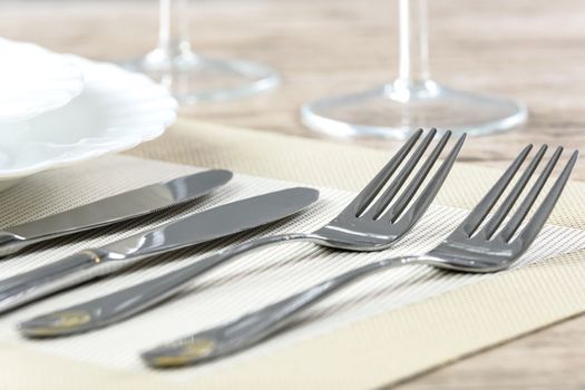 Elegant restaurant table setting with plates cutlery and stemware on a wooden table