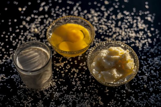 Close up shot of ayurvedic method or calcium supplement on the black surface consisting of raw eggs, milk, and ghee or clarified butter along with some sugar as a sweetener.