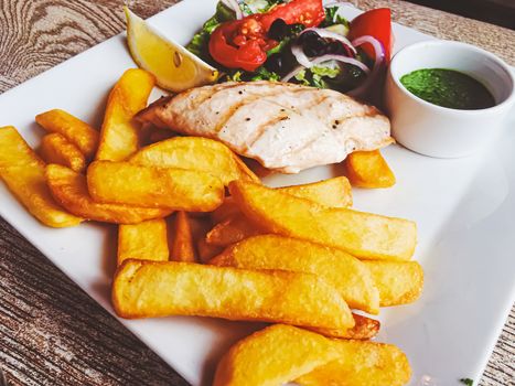 Grilled chicken, french fries and salad for lunch, served meal