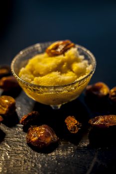 Close up shot of dates soaked in ghee for better stamina and health on black wooden surface along with ghee or clarified butter. Vertical shot.