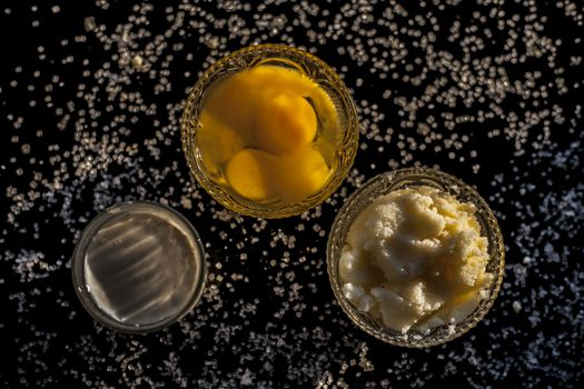 Close up shot of ayurvedic method or calcium supplement on the black surface consisting of raw eggs, milk, and ghee or clarified butter along with some sugar as a sweetener.