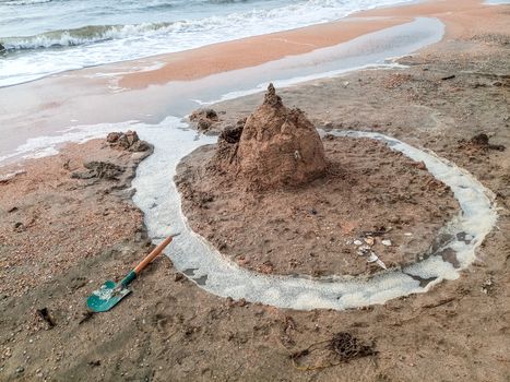 Sand castle on the beach with shells. Children's games at sea.