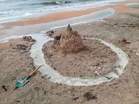 Sand castle on the beach with shells. Children's games at sea.