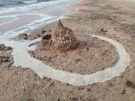 Sand castle on the beach with shells. Children's games at sea.