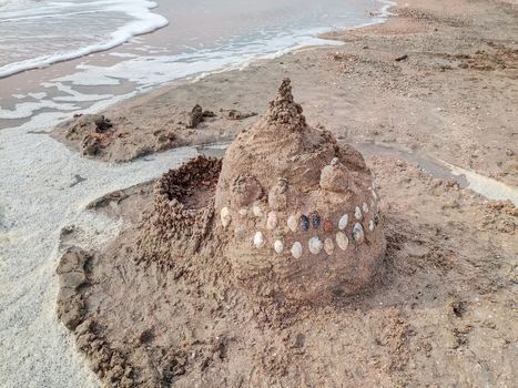 Sand castle on the beach with shells. Children's games at sea.