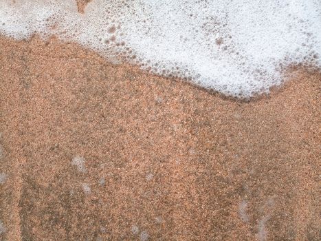 The Mor wave on the coastal sand, the background texture of the sea wave and foam on the sand.