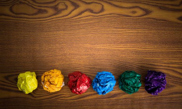 crumpled colorful paper on wooden background