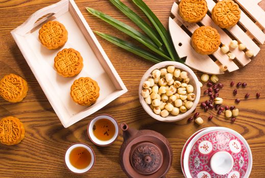 Traditional mooncakes on table setting with ingredients and teapot. Translation for those chinese words is red bean, lotus paste and jade paste.