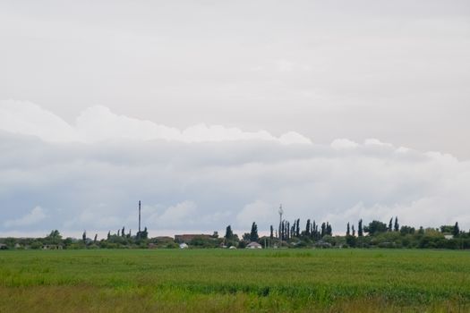 Cloudy landscape, the village before the rain, visible large cumulus clouds and clouds over the village.