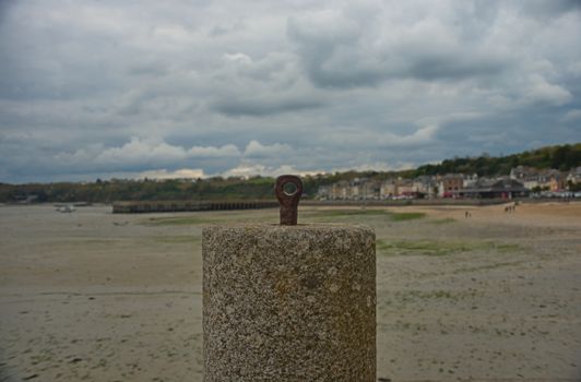 Concrete block for anchoring boats with sandy beach coastal town in background