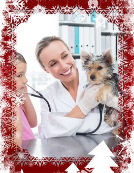 Vet with girl examining puppy in clinic against christmas themed frame