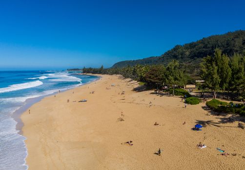 Locals and tourists on the sand beach at Banzai Pipeline on north coast of Oahu, Hawaii