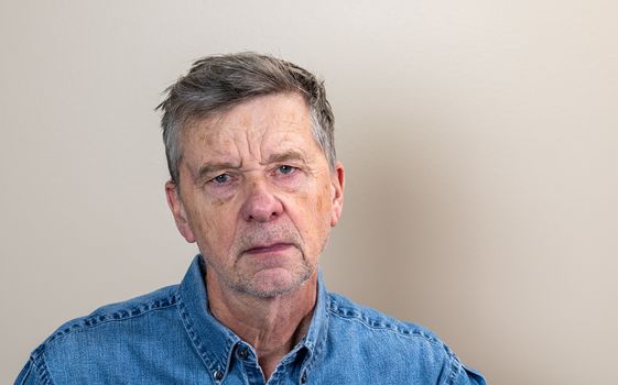 Head and shoulders portrait of a senior caucasian man unshaven and facing camera