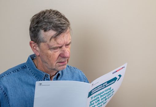 Worried senior man reading rules for transporting good to Europe in the event of no deal Brexit