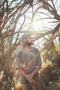 Young man with a beard is looking at the forest on a beautiful sunset in the mountains