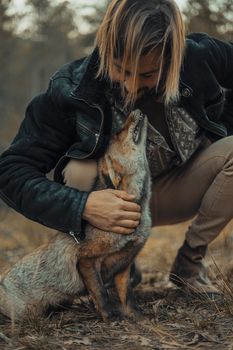Bearded young man with a wild fox in the mountains