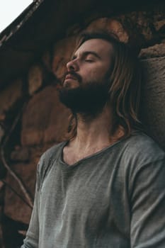 Bearded young man meditating on the farmhouse wall