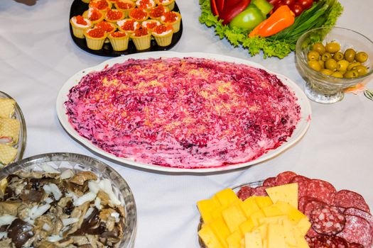 Herring salad under a fur coat. Different dishes on the table