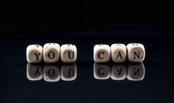 wooden blocks with the text you can on a black background