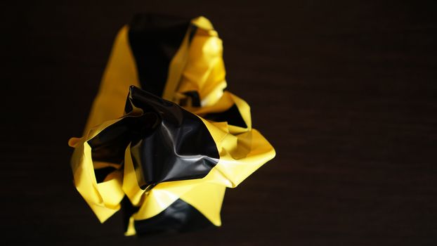 Crumpled yellow and black tapes on dark background