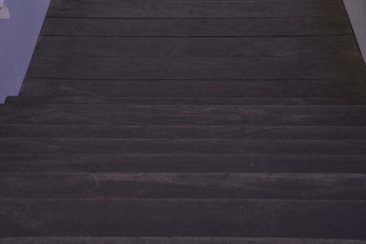 Stair with dark wood steps, downward, dark, lines parallel symmetry