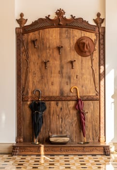 Old fashioned wooden hat, coat and umbrella stand in hallway on marble floor