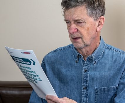 Worried senior man reading rules for transporting good to Europe in the event of no deal Brexit