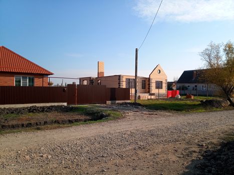 A new house with an orange roof and a brown fence.