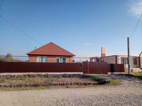 A new house with an orange roof and a brown fence.