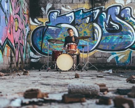 Young man playing drums in an underground environment