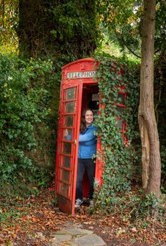 Woman opening the door from a red traditional telephone box in England