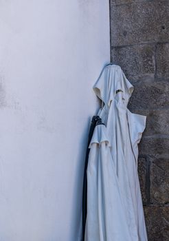 Folded street or table umbrella looks like a ghostly cloth costume with hood and eyes