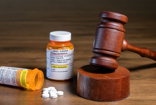 Oxycodone is the generic name for opoid pain killing tablets. Prescription bottle for pills and tablets with judge's gavel for court decision