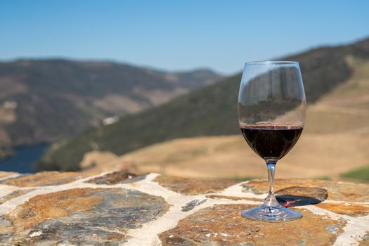 Glass of red wine or port for tasting above the hillsides of the Douro valley in Portugal