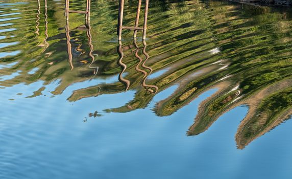 Wavy stakes and wooden poles for boat moorings and anchors reflected in calm Douro river in Portugal