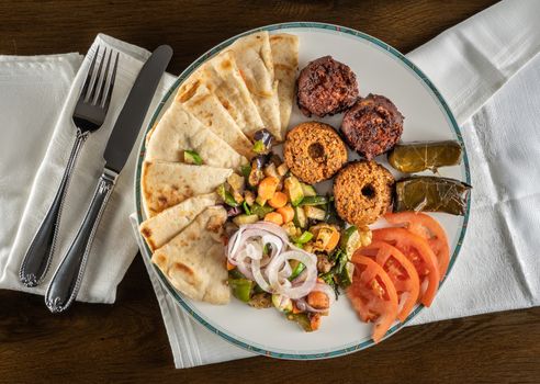 From above view of greek vegetarian sample with falafel, pita and dolmades takeout food plated at home with napkin