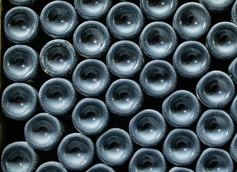 Stacks of wine bottles laying flat in wooden racks in old wine cellar or cave