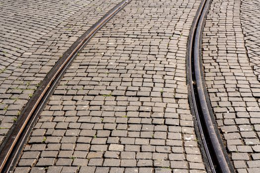 Curve of steel rails from tramcar track set into stone cobble pattern in Porto
