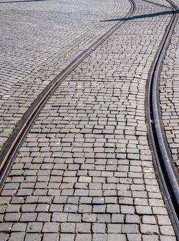 Curve of steel rails from tramcar track set into stone cobble pattern in Porto