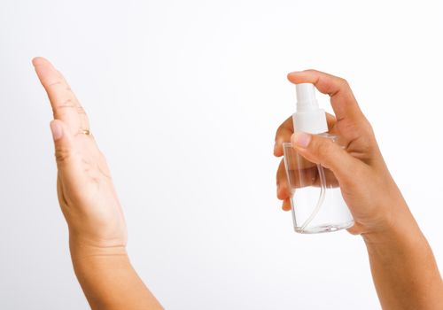 Closeup Hand Asian young woman applying spray pump dispenser sanitizer alcohol on hand wash cleaning, hygiene prevention COVID-19 or coronavirus protection concept, isolated on white background