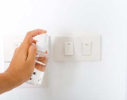 Asian young woman applying press dispenser sanitizer alcohol spray squirt to light switch wash cleaning, hygiene prevention COVID-19 or coronavirus protection concept, isolated on white background