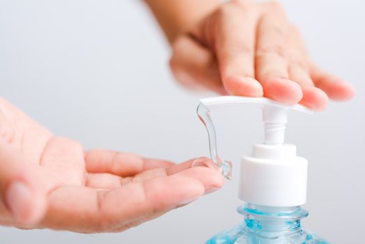 Close up Asian young woman applying press dispenser sanitizer alcohol gel pump to hand wash cleaning, hygiene prevention COVID-19 or coronavirus protection concept, isolated on white background