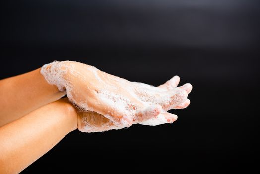 Closeup body care Asian young woman washing hands with soap have foam, hygiene prevention COVID-19 or coronavirus protection concept, isolated on black background