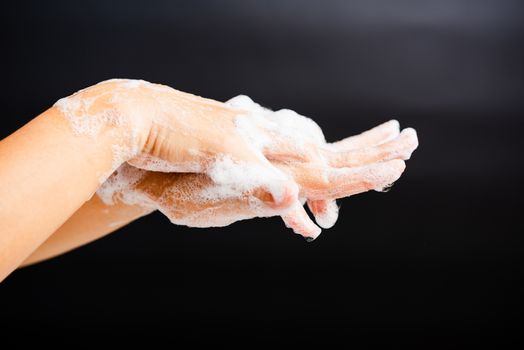 Closeup body care Asian young woman washing hands with soap have foam, hygiene prevention COVID-19 or coronavirus protection concept, isolated on black background