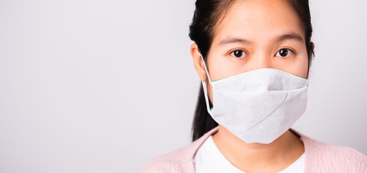 Asian beautiful woman wearing protection face mask against coronavirus her looking to camera, studio shot isolated on white background with copy space, COVID-19 or corona virus concept